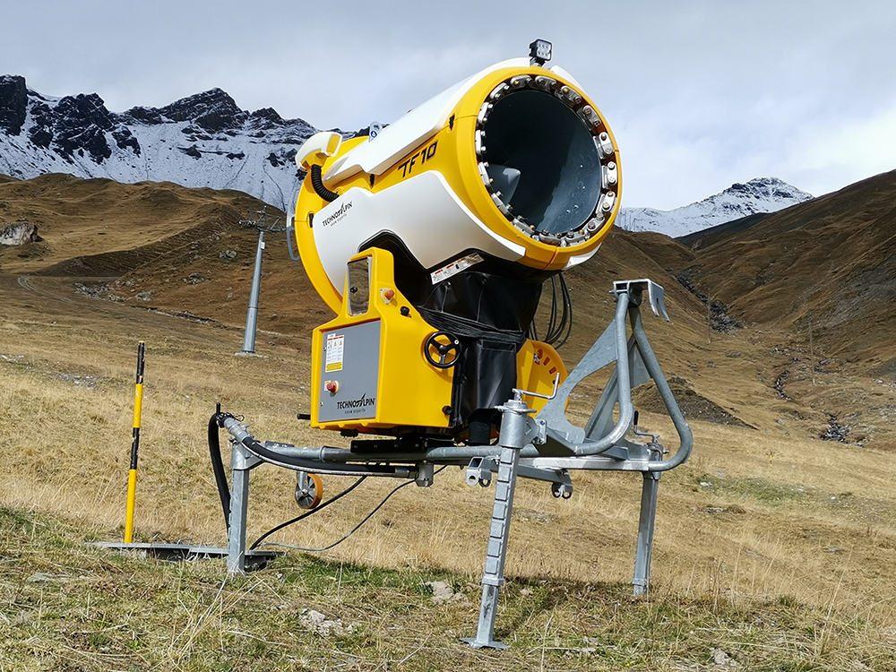 snow gun on brown grassland in the alps snow gun on brown grassland in the alps