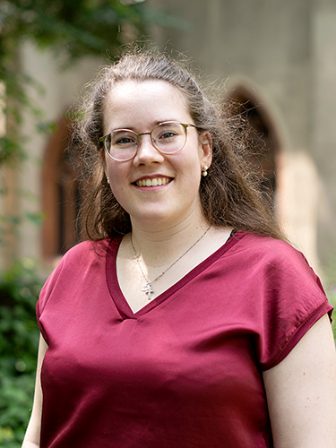 Porträt einer Frau mit langen braunen Haaren, Brille und bordeauxfarbener Bluse Porträt einer Frau mit langen braunen Haaren, Brille und bordeauxfarbener Bluse