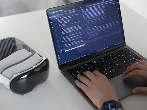 Blick auf den Laptop-Screen mit Code, daneben die XR-Brille Blick auf den Laptop-Screen mit Code, daneben die XR-Brille