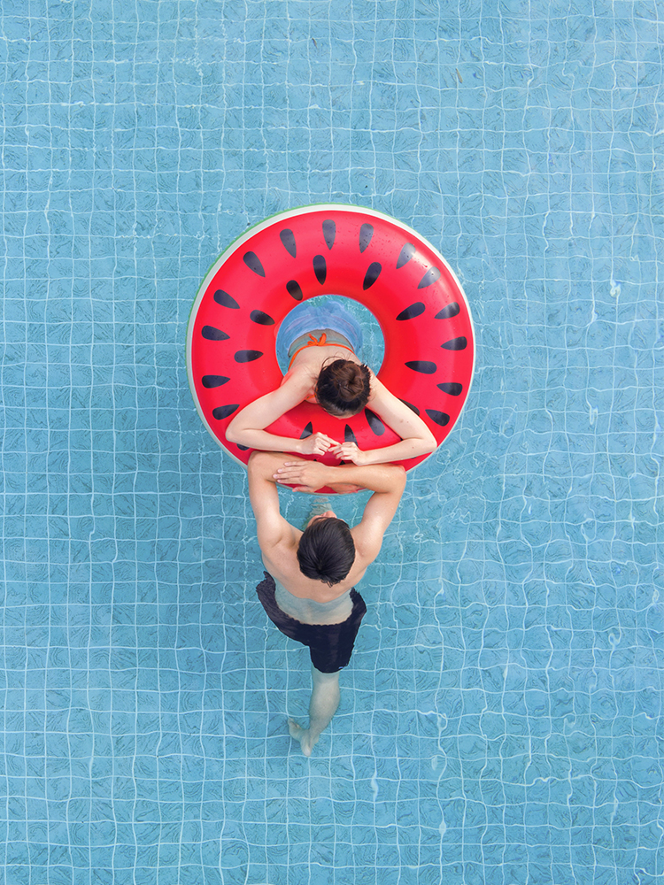 A couple in a swimming pool with a swimming hoop separating them. A couple in a swimming pool with a swimming hoop separating them.