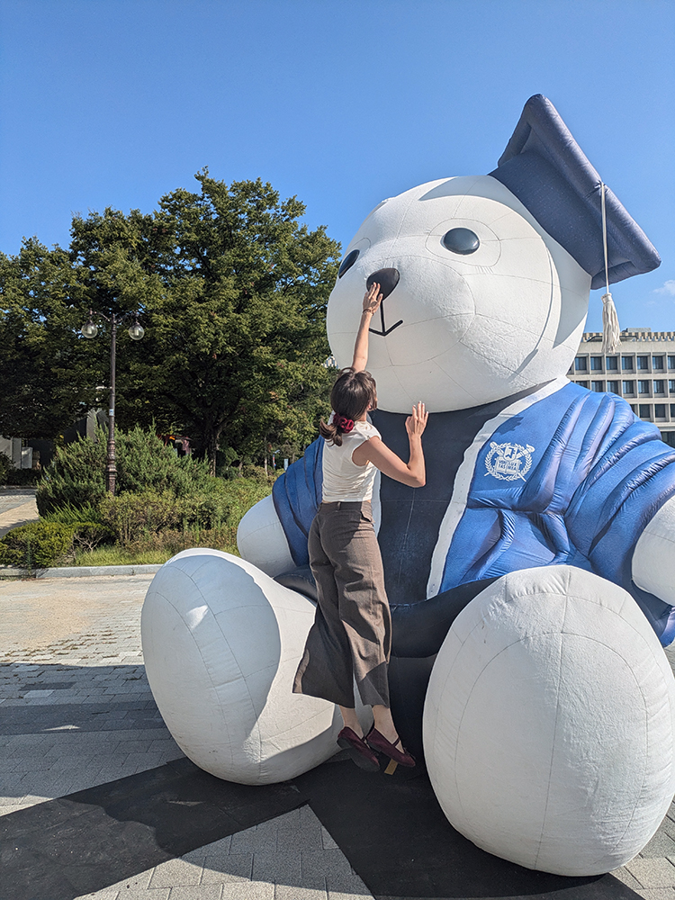 Anna berührt die Nase vom Snoo-Bär, einer grossen aufblasbaren Bärenstatue in einem Abschlussgewand. Anna berührt die Nase vom Snoo-Bär, einer grossen aufblasbaren Bärenstatue in einem Abschlussgewand.