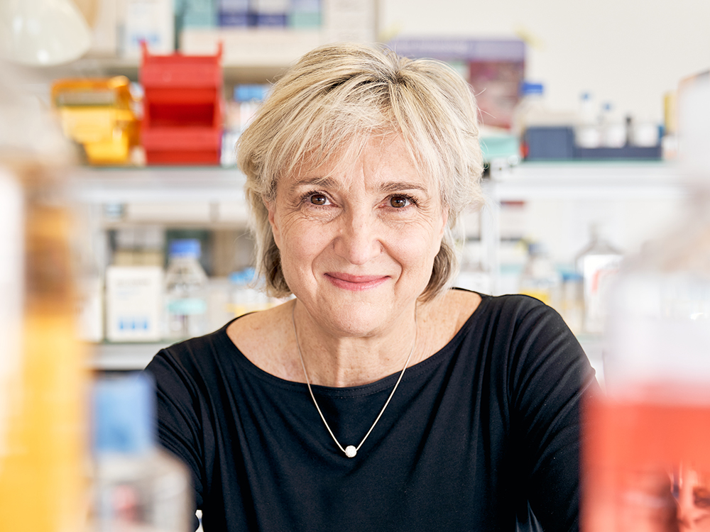 Portrait of Lucia Mori in the laboratory between bottles filled with yellow and red liquids Portrait of Lucia Mori in the laboratory between bottles filled with yellow and red liquids